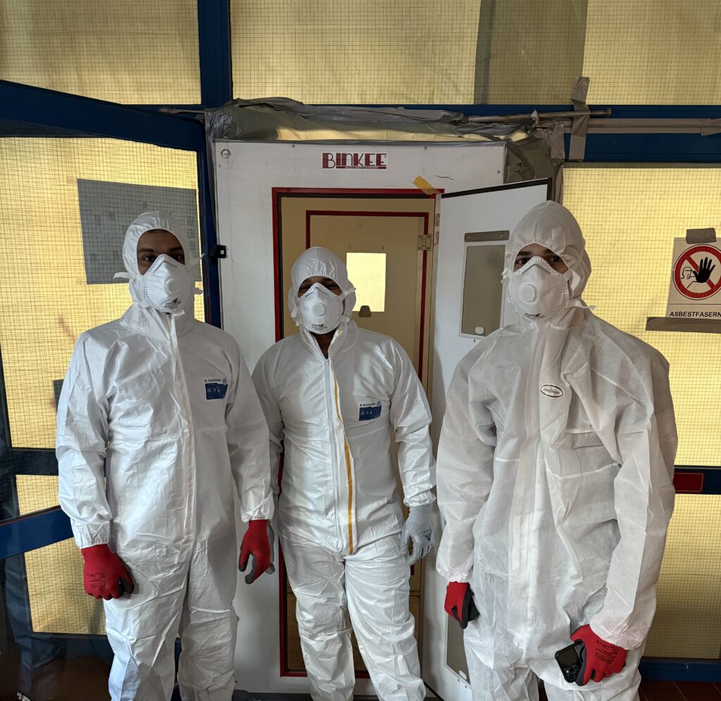 Arbeiter in Schutzanzügen und Atemschutzmasken während der Asbestsanierung – Bau2Day